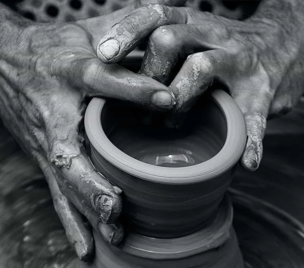 Black and white photo of hands shaping clay on a potter’s wheel, from the Your Brain on Art website